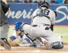  ??  ?? Toronto Blue Jays catcher Russell Martin is tagged out at home plate by New York Yankees catcher Austin Romine in the second inning in Toronto on Sunday. The Jays won the game 7-4.