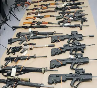 ??  ?? Part of a cache of firearms is displayed in Campbell River. RCMP seized more than 100 guns, including handguns, shotguns and assault-style rifles.