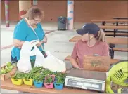  ?? Doug Walker ?? Trudy Barker buys some fresh veggies at the Ridge Ferry Farmers Market from Brittney Hampton with Cook Farm in Lyerly.