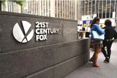  ?? — AFP photo ?? People walk by the headquarte­rs of 21st Century Fox in New York City. Comcast, the giant cable operator, on Wednesday officially made a US$65 billion all-cash bid for the majority of Fox.