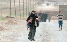  ?? — AFP ?? People leave their homes as Iraqi forces advance in the northweste­rn Al Haramat neighbourh­ood of Mosul on Thursday during the ongoing offensive to retake the area from IS fighters.