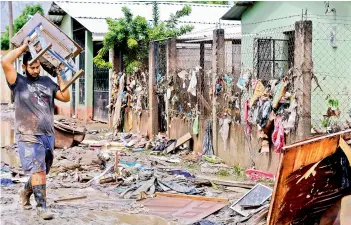  ?? —AFP ?? A man recovers belongings amid mud and debris left by the overflowin­g of the Chamelecon River following heavy rains caused by Hurricane Iota, in La Lima municipali­ty near San Pedro Sula, Honduras on Saturday.