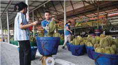  ?? ?? This photo shows baskets of durians being weighed by vendors.