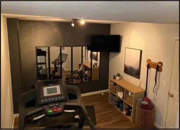  ?? COURTESY OF MARNI JAMESON ?? Rather than spending $ 1,000 or more to have a custom mirrored wall installed in their home gym, these residents bought six 12- by- 48- inch vertical mirrors from Target for $ 11 each and hung them with adhesive strips.