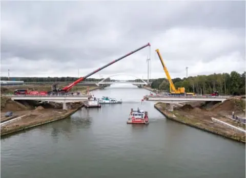  ?? FOTO RR ?? Het bruggedeel­te boven het water is verwijderd, de rest komt de volgende dagen aan de beurt. Achteraan de nieuwe boogbrug die over twee maanden naar haar plaats wordt gevaren.