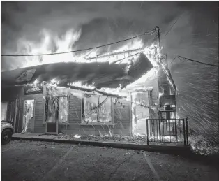  ?? AP PHOTO ?? Flames consume The Screen &amp; Window Shop as the Camp Fire tears through Paradise, Calif., on Thursday. Tens of thousands of people fled a fast-moving wildfire in Northern California, some clutching babies and pets as they abandoned vehicles and struck out on foot ahead of the flames that forced the evacuation of an entire town and destroyed hundreds of structures.