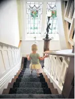  ??  ?? Harper Simms (3) descends the stairs, passing stained glass windows that used to be in an old farmhouse in England and that were recently installed in Islington.