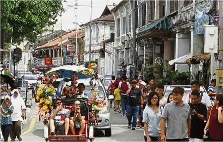  ??  ?? Sightseein­g: Tourists exploring the inner city in Lebuh Cannon in George Town.