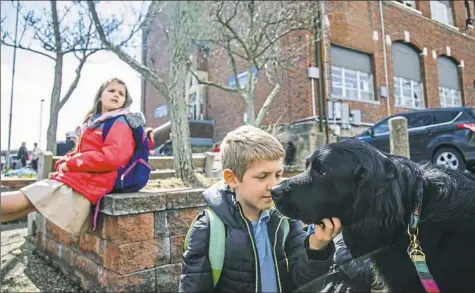  ?? Andrew Rush/Post-Gazette ?? Sam Bleakley, 10, of Bellevue, pets his dog, Teddy, after classes at Assumption School in Bellevue on Monday. Sam walks to and from school with his mother, Katie, and Teddy.