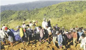  ??  ?? Jade mine workers and rescue members carrying victims of a landslide walk on dump soil in Hpakant, Kachin State, Myanmar. —AP