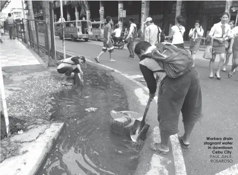  ?? PAUL JUN E. ROSAROSO ?? Workers drain stagnant water in downtown
Cebu City.