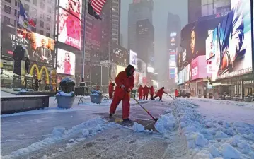  ?? — AFP ?? Men plow snow at the Times Square during a snowstorm in New York on Tuesday. Winter storm Stella dumped snow and sleet across the northeaste­rn US, where thousands of flights were cancelled and schools closed.