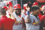  ?? The Associated Press ?? RECORD-SETTING CARDS: St. Louis Cardinals’ Marcell Ozuna, left, and Yadier Molina, are greeted by teammates after scoring off Tommy Edman’s double Wednesday during the first inning of Game 5 of the National League Division Series game against the Atlanta Braves in Atlanta.