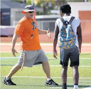  ?? PHELAN M. EBENHACK/ORLANDO SENTINEL ?? Boone assistant coach Charles Nassar, left, directs defensive players during first day of practice on Monday.