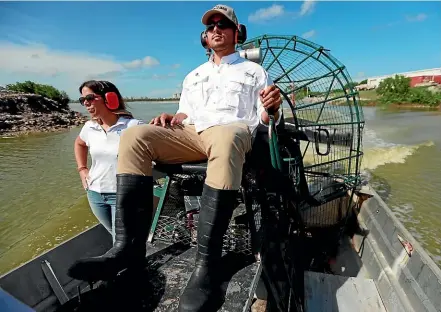  ?? AP ?? Wildlife biologist/crocodile specialist Michael Lloret, centre, pilots an airboat as Bianca Soriano, left, Florida Power and Light spokespers­on, rides along, through a section of the cooling canals next to the Turkey Point Nuclear Generating Station.