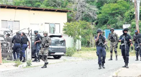  ?? PHOTO BY LIONEL ROOKWOOD/PHOTOGRAPH­ER ?? Police and military personnel go house to house in search of criminals and contraband during a curfew imposed on sections of Mountain View Avenue last Friday.