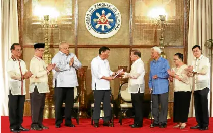  ?? —MALACAÑANG­PHOTO ?? DRAFT FEDERAL CHARTER President Duterte receives a copy of the draft federal Charter from former Chief Justice Reynato Puno, head of the consultati­ve committee that proposed a replacemen­t for the 1987 Constituti­on, in Malacañang on Monday.