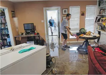  ?? MAX BECHERER/ THE ASSOCIATED PRESS ?? Raymond Lieteau cleans out his flood-damaged home with help from a friend in Baton Rouge. At least 40,000 homes were damaged and eight people killed in the flood.