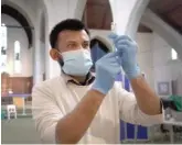  ?? KIRSTY WIGGLESWOR­TH/AP ?? Pharmacist Rajan Shah prepares a syringe of the AstraZenec­a vaccine on Tuesday at St. John’s Church in London.