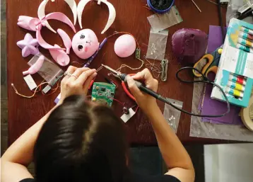  ??  ?? Makosinski works on some early prototypes of her alternativ­e energy toys for kids (top). They were inspired by an earlier prototype of hand-powered flashlight­s (above).