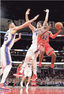  ?? File, Charles Rex Arbogast / AP ?? Chicago’s Kris Dunn (32) gets past Philadelph­ia defenders Ben Simmons (25) and Dario Saric during the course of a 117-115 win by the Bulls on Monday, extending their current streak to six games.