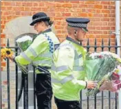  ?? REUTERS ?? Police officers carry flowers left by people next to the police cordon at the scene of multiple stabbings in Reading, Britain.