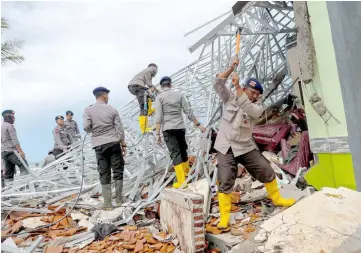  ??  ?? Police officers search for victims among rubble of a destroyed beach front hotel in Pandeglang, Banten province, Indonesia. — Reuters photo