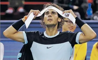  ?? DAMIR SAGOLJ / REUTERS ?? Nadal se coloca la cinta para sujetar el cabello durante un descanso del partido ante el francés Tsonga