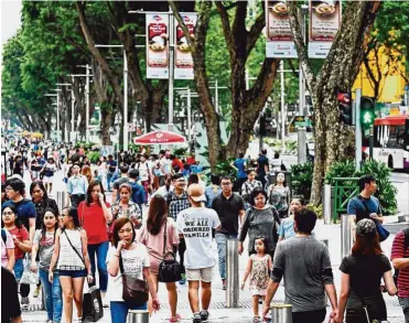  ?? — ST Photo ?? Cash preferred: A file picture showing people walking along Orchard Road in Singapore. Fortythree per cent of those surveyed by Paypal say they use cash most often, compared with 25% in China.