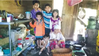  ??  ?? KAMSIAH bersama cucu yang dijaganya di Kg Nyaris-Nyaris. (Gambar bawah) Kamsiah (duduk) dikekeling­i cucu-cucunya sambil dibantu oleh Shamil (tengah, tunduk) semasa membuat kuih cincin di dapur rumahnya yang usang.