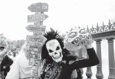  ?? SAMEER AL-DOUMY/GETTY-AFP ?? Protests in France: A protester wearing a mask of a human skull holds a sign in French reading “All the roads lead to COVID” during a protest against the vaccinatio­n and the compulsory health pass called for by the French government, in Paris on Saturday. Some 160,000 people took to the streets as legislator­s debated the virus bill.