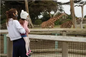  ??  ?? A woman holds a child while viewing giraffes at the San Francisco Zoo on Monday in San Francisco. (AP Photo/Ben Margot)