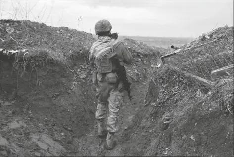  ?? ANDRIY DUBCHAK/AP ?? A UKRAINIAN SOLDIER HOLDS A CAT AND WALKS IN A TRENCH on the line of separation from pro-Russian rebels near Debaltsevo, Donetsk region, Ukraine, on Friday. Russia-West tensions escalated recently with Ukraine and its Western backers becoming increasing­ly concerned that a Russian troop buildup near the Ukrainian border could signal Moscow’s intention to invade.