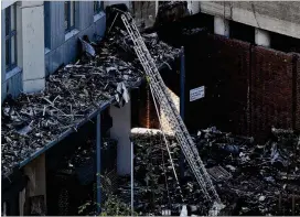  ?? DAN KITWOOD / GETTY IMAGES ?? A ladder extends inside the rubble of Grenfell tower as it continues to smolder in June in London, England. Firefighte­rs are angry about the lack of fire equipment and say higher ladders would have prevented the loss of 80 lives in the fire.