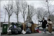  ?? AP PHOTO/MICHEL EULER ?? People walk past not collected garbage cans near the Eiffel Tower in Paris, Sunday, March 12, 2023. A contentiou­s bill that would raise the retirement age in France from 62to 64got a push forward with the Senate’s adoption of the measure amid strikes, protests and uncollecte­d garbage piling higher by the day.