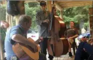  ?? MARGIE MASON — THE ASSOCIATED PRESS ?? Mike Baughman, center, plays the bass with Sam Gibson, left, on guitar while Ryan Baughman, right, looks on at a cabin in Herald, W.Va. Mike Baughman is fighting a rare bile duct cancer he believes is a result of ingesting a parasite inside raw fish...