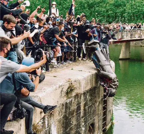  ?? (GIULIA SPADAFORA/NURPHOTO) ?? La statue du négrier et mécène Edward Colston, jetée par la foule, dimanche, dans l’Avon.