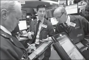  ?? AP/RICHARD DREW ?? Specialist Thomas McArdle (center) works with traders Wednesday at his post on the floor of the New York Stock Exchange.