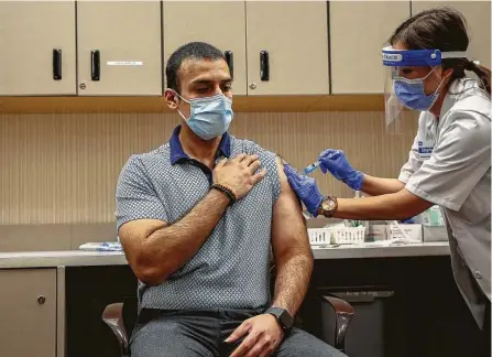  ?? Godofredo A. Vásquez / Staff photograph­er ?? Kroger pharmacist Stephanie Phan administer­s a dose of Moderna COVID-19 vaccine to Nabeel Sattar, pharmacy manager. Pharmacies big and small are trying to keep up with rising public demand and still keep their employees safe.