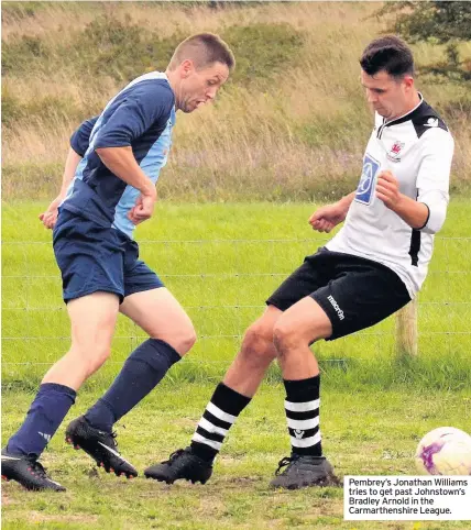  ??  ?? Pembrey’s Jonathan Williams tries to get past Johnstown’s Bradley Arnold in the Carmarthen­shire League.