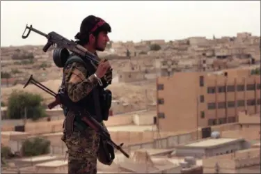  ?? PHOTOS BY THE ASSOCIATED PRESS ?? This April 30photo provided by the Syria Democratic Forces (SDF), shows a fighter from the SDF carrying weapons as he looks toward the northern town of Tabqa, Syria.