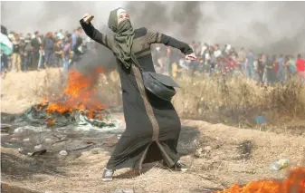  ??  ?? A girl hurls stones during a protest at the Israel-gaza border, east of Gaza City, on Friday. — Reuters