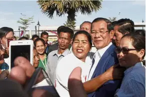  ?? — AP ?? Camera-ready: Hun Sen posing for a photo with villagers and admirers in Phnom Penh.