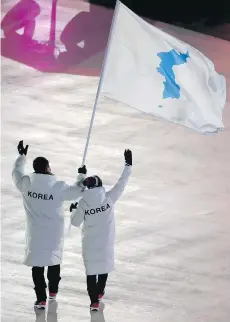  ?? SEAN M. HAFFEY/AFP/GETTY IMAGES ?? At right, South Korean bobsledder Won Yun-jong, left, and North Korean hockey player Hwang Chung Gum represent Unified Korea.