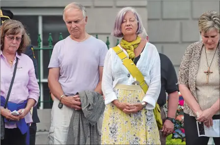  ?? DANA JENSEN/THE DAY ?? People bow their heads during a moment of silence during the Norwich vigil honoring the victims of violence in Charlottes­ville at the David Ruggles Freedom Courtyard at Norwich City Hall on Tuesday.