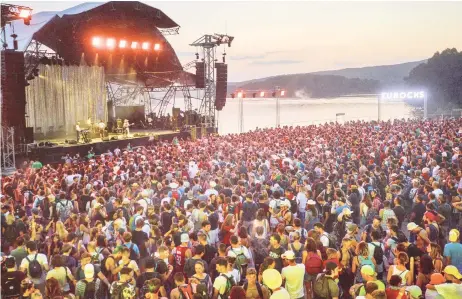  ?? — AFP photo ?? In this file photo show audience members cheer as a band perform on stage during the 29th Eurockeenn­es rock music festival on July 7, 2017 in Belfort, eastern France. The Eurockeenn­es de Belfort music festival which was to be held from July 2 until July 4 has been cancelled as French President announced on the eve that big festivals could not take place until mid-July at the earliest in an effort to curb the spread of the coronaviru­s (Covid-19) pandemic.