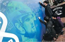  ?? NICK PROCAYLO/PNG ?? Fans write messages to the Sedin twins on a wall at Toyota Plaza, outside Rogers
Arena, before Thursday’s game against the Arizona Coyotes.