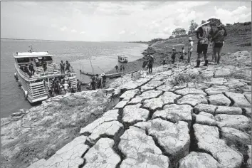  ?? Edmar Barros Associated Press ?? RIVERSIDE residents carry aid amid drought fueled by anthropoge­nic climate change in Brazil’s Amazonas state last year. In the Northern Hemisphere, climate change contribute­d to 2023’s record-setting summer.