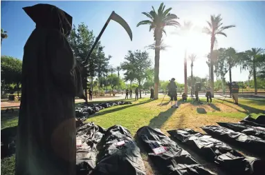  ?? PHOTOS BY DAVID WALLACE/THE REPUBLIC ?? An individual dressed as the grim reaper stands alongside dozens of ersatz body bags at a rally Tuesday at the Arizona State Capitol opposing repeal of Gov. Doug Ducey’s stay-at-home order.