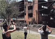  ?? T.J. KIRKPATRIC­K, GETTY IMAGES ?? Bystanders take photos Thursday after an overnight explosion and fire destroyed an apartment building in the Flower Branch Apartments complex in Silver Spring, Md.